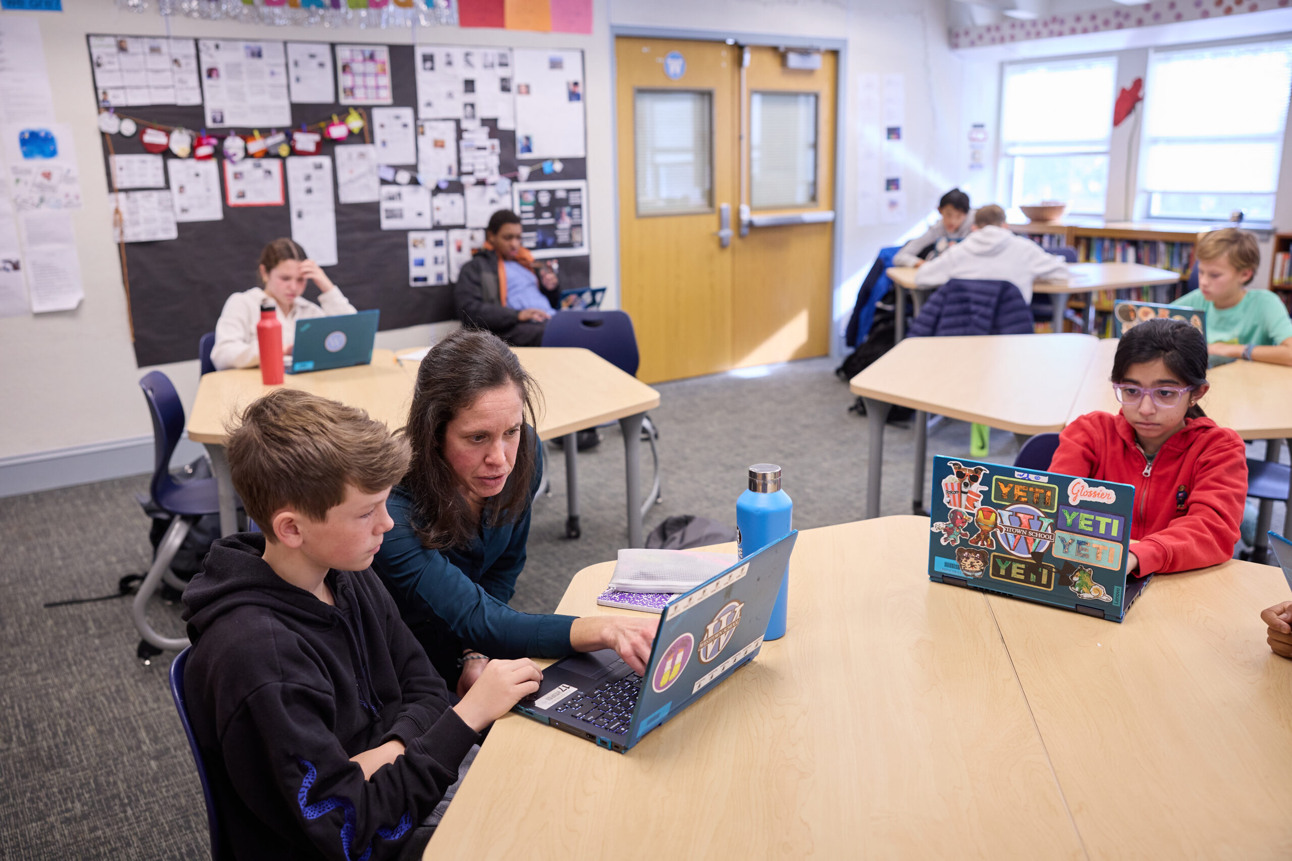 a teacher helps a Middle School student on their computer